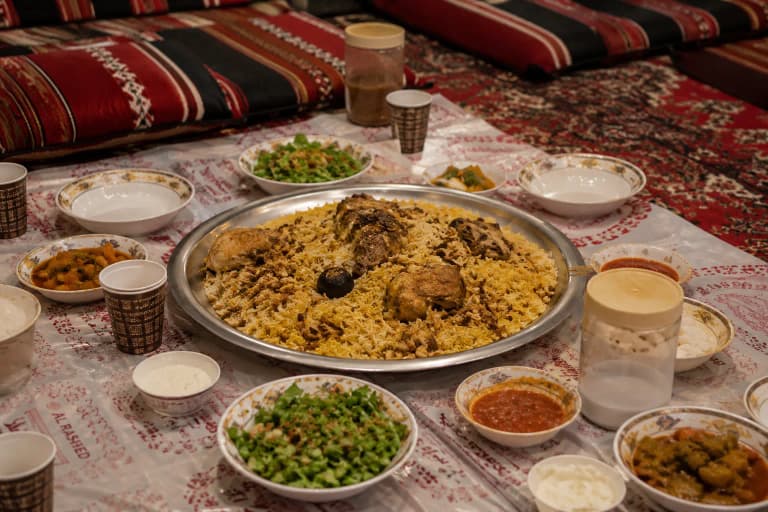 Traditional Saudi kabsa feast served on the floor with people sitting around a communal platter
