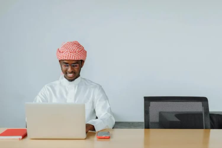 Saudi professional smiling while working at a modern office desk